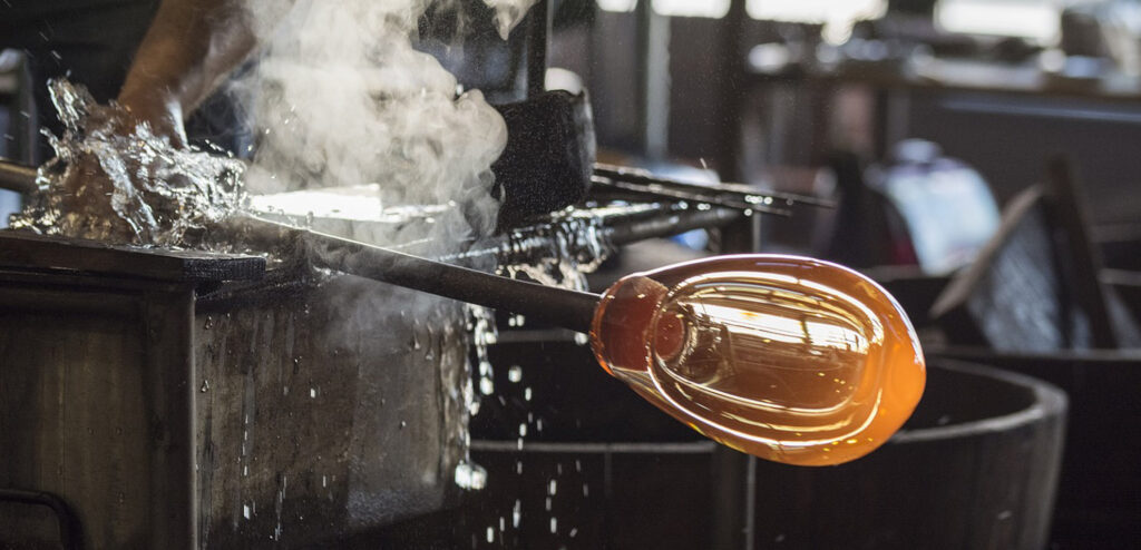 Szene aus einer Glasbläserei mit gelbem aufgeblasenem Glasball.