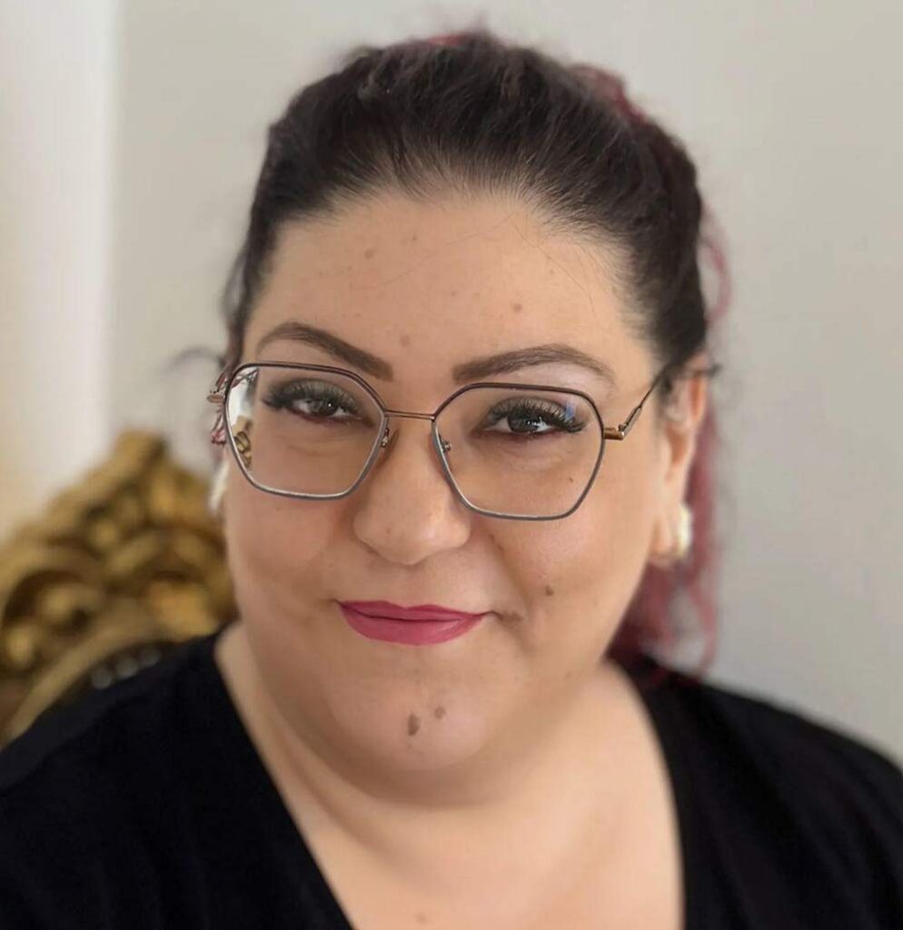 Porträt einer dunkelhaarigen Frau (Francesca Tritto) mit Brille und zurückgebundenen Haaren, lächelt dezent in die Kamera.